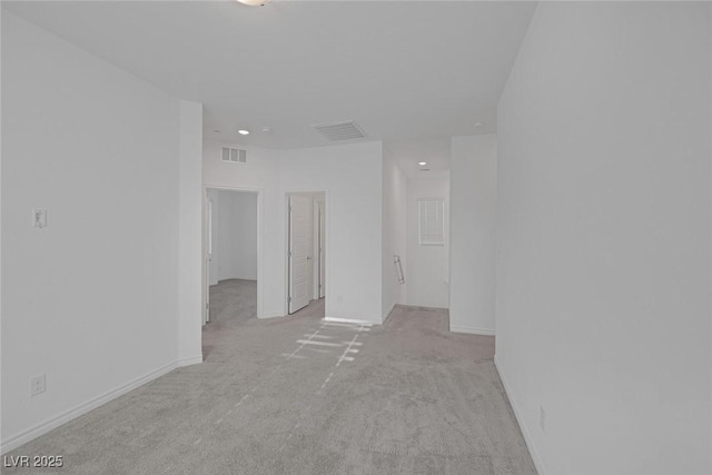 unfurnished room with visible vents, light carpet, and baseboards