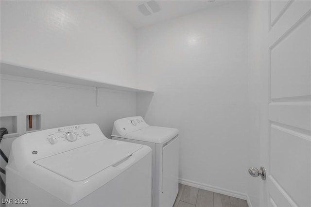 laundry room with washing machine and dryer, laundry area, baseboards, and light wood finished floors