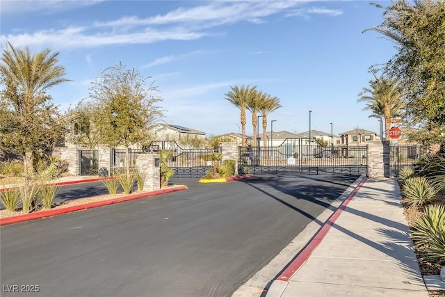 view of street with sidewalks, a gate, a gated entry, and curbs