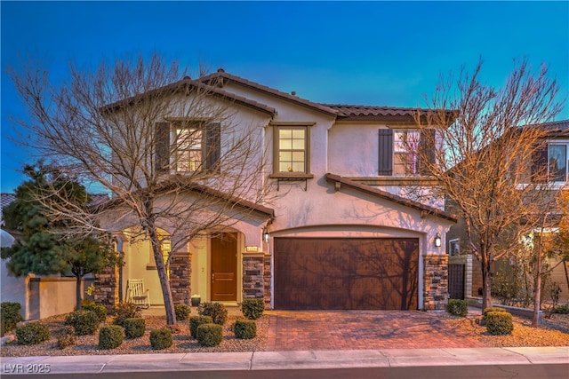 view of front of property with a garage, stone siding, a tiled roof, decorative driveway, and stucco siding