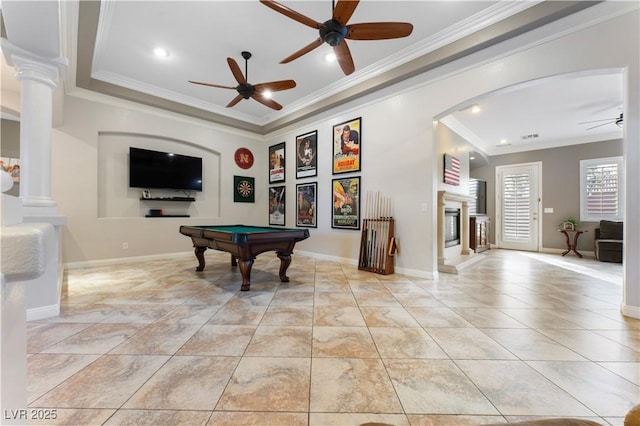 playroom featuring decorative columns, baseboards, a glass covered fireplace, ceiling fan, and ornamental molding