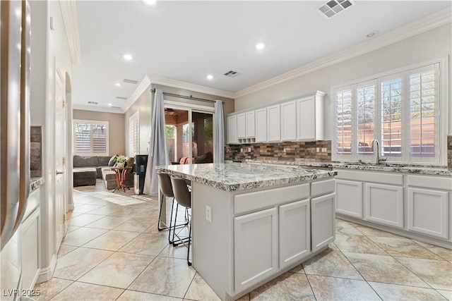 kitchen with a center island, a sink, visible vents, and decorative backsplash