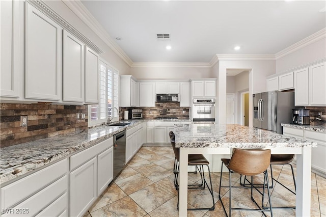 kitchen with a center island, a breakfast bar area, visible vents, appliances with stainless steel finishes, and a sink