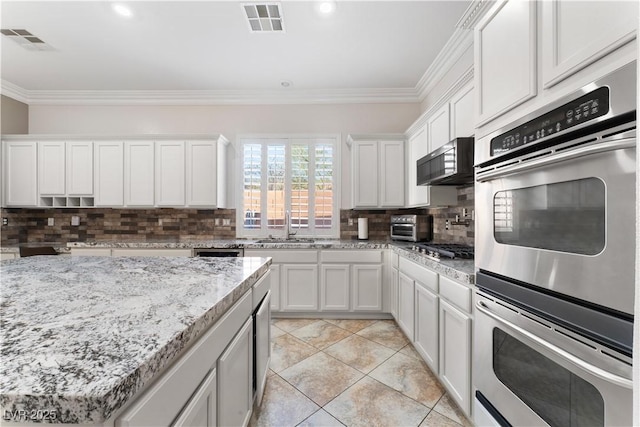 kitchen with stainless steel appliances, a sink, visible vents, ornamental molding, and backsplash