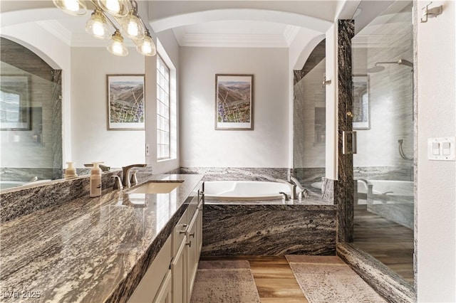 bathroom with a stall shower, wood finished floors, a garden tub, crown molding, and vanity