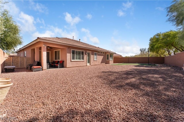 rear view of house with a ceiling fan, a patio area, a fenced backyard, and stucco siding