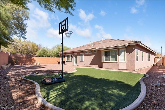 back of house with a fenced backyard and stucco siding