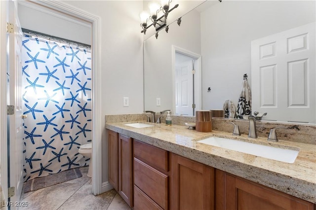 full bathroom featuring toilet, double vanity, a sink, and tile patterned floors