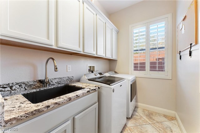 clothes washing area with light tile patterned floors, cabinet space, washing machine and dryer, a sink, and baseboards