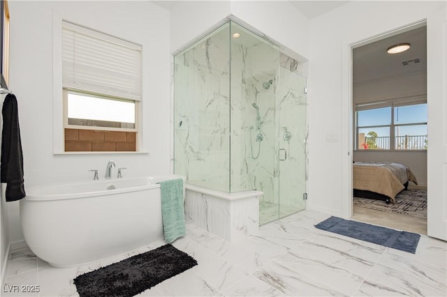 ensuite bathroom with marble finish floor, a healthy amount of sunlight, a freestanding tub, and a marble finish shower