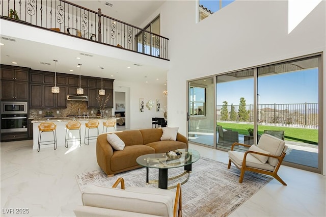 living area featuring recessed lighting, marble finish floor, visible vents, and a towering ceiling