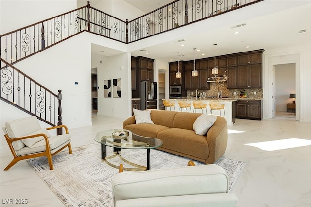 living room with visible vents, a towering ceiling, stairway, marble finish floor, and recessed lighting