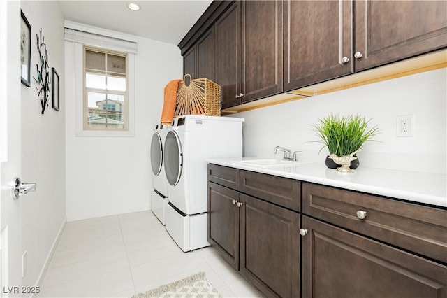 laundry area with light tile patterned floors, washing machine and dryer, a sink, baseboards, and cabinet space