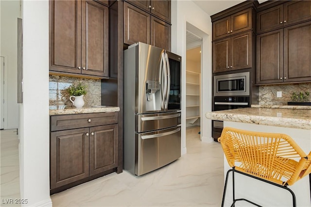 kitchen featuring marble finish floor, stainless steel appliances, tasteful backsplash, and dark brown cabinetry