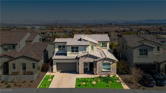 mediterranean / spanish-style house with stucco siding, a residential view, decorative driveway, and a tiled roof