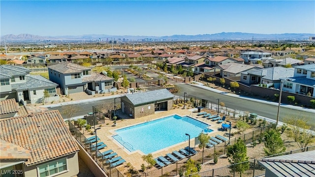 community pool with a mountain view, an outdoor structure, fence, and a residential view