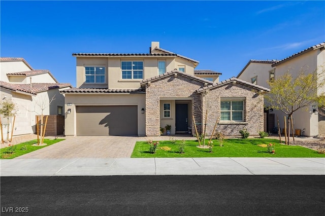 mediterranean / spanish house featuring an attached garage, stone siding, decorative driveway, stucco siding, and a front lawn