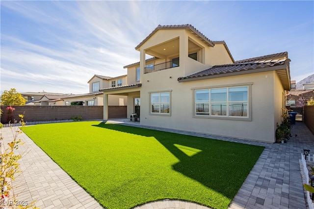 back of house with a patio, a yard, stucco siding, a balcony, and a fenced backyard