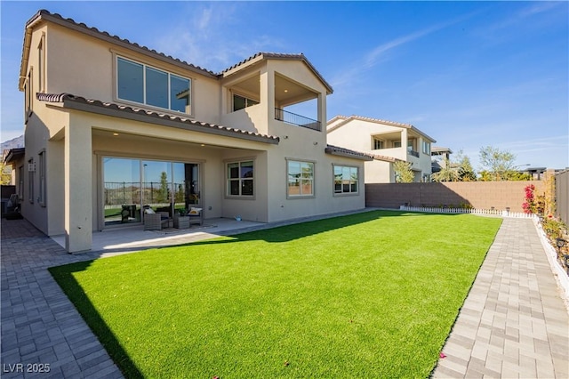 back of house featuring a yard, a fenced backyard, a patio, and stucco siding