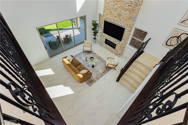 living area featuring marble finish floor, stairway, and a towering ceiling