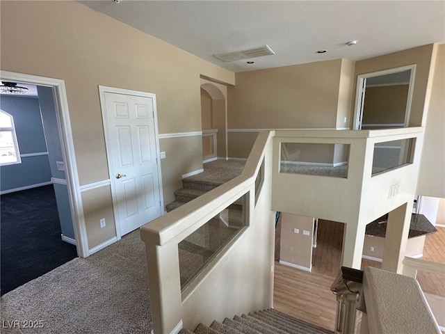 staircase featuring carpet floors, visible vents, and baseboards