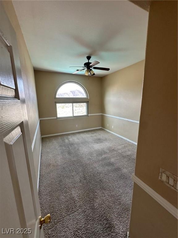 carpeted spare room with baseboards and a ceiling fan