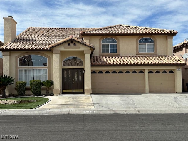 mediterranean / spanish-style home featuring concrete driveway, a chimney, an attached garage, and stucco siding