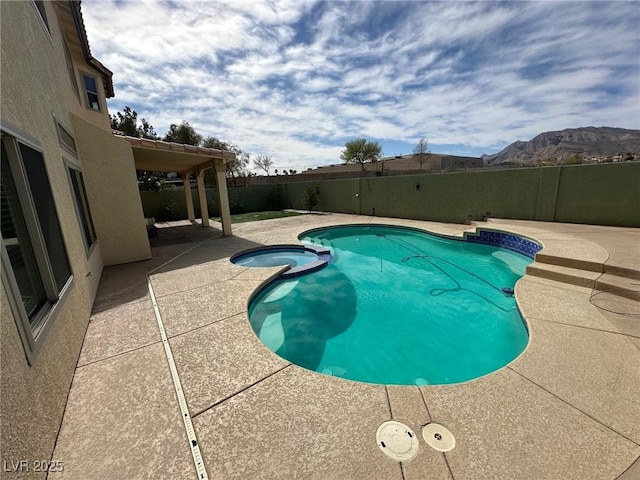 view of pool featuring a mountain view, a patio area, a fenced backyard, and a pool with connected hot tub