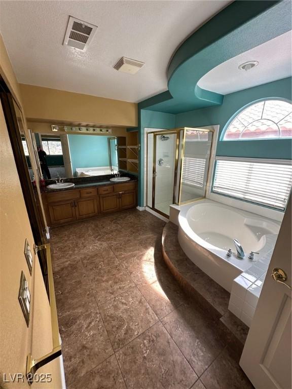 bathroom featuring a bath, a shower stall, visible vents, and a textured ceiling