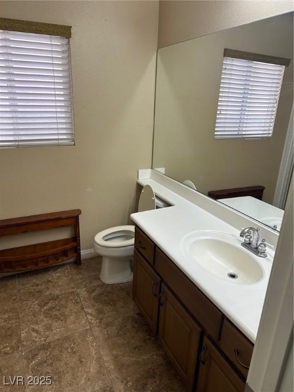 bathroom with baseboards, vanity, and toilet