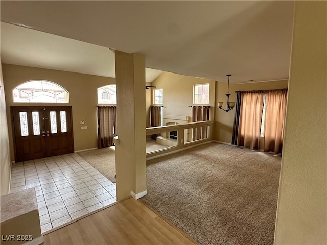 foyer entrance featuring carpet floors, baseboards, vaulted ceiling, and tile patterned floors