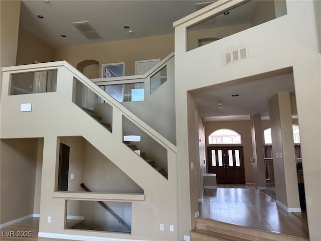 entryway featuring a towering ceiling, visible vents, and baseboards