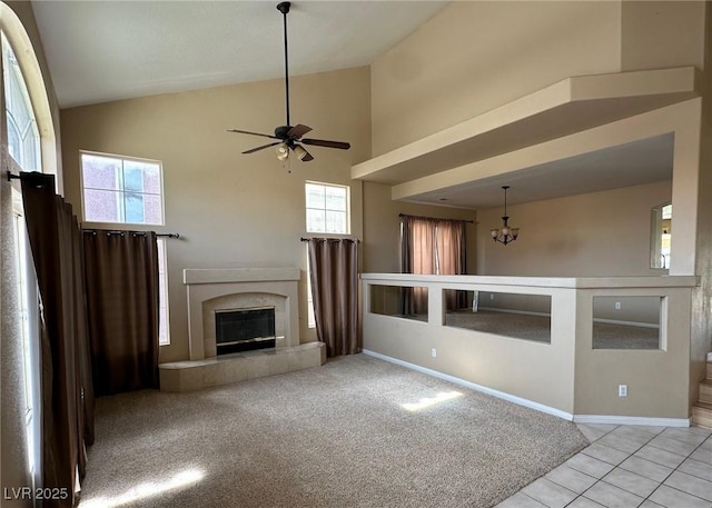 unfurnished living room with baseboards, high vaulted ceiling, carpet flooring, and a tile fireplace