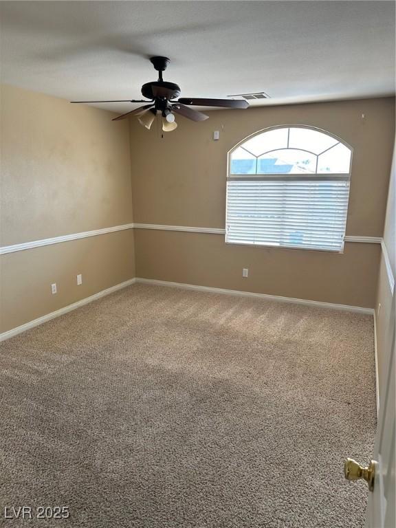 carpeted empty room featuring ceiling fan and baseboards