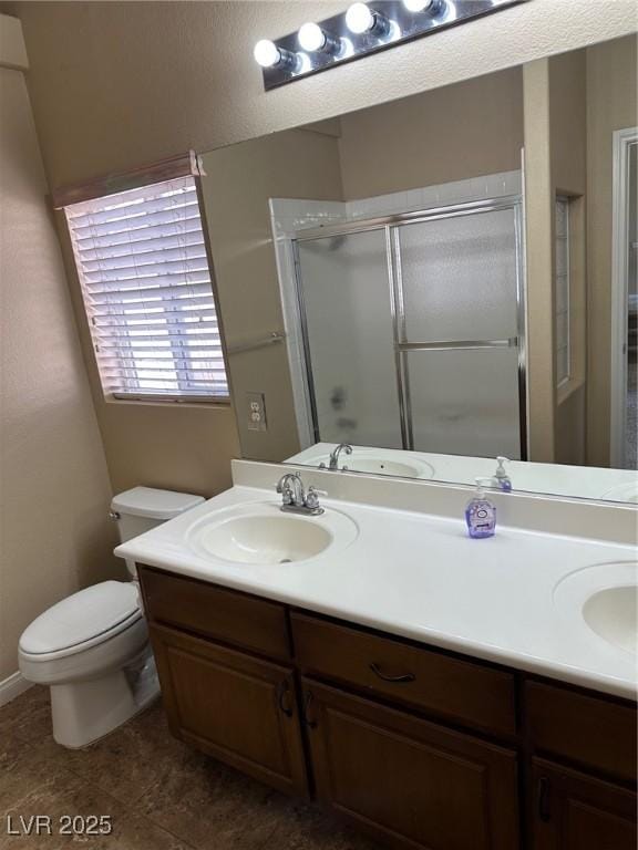 bathroom featuring a sink, a shower stall, toilet, and double vanity