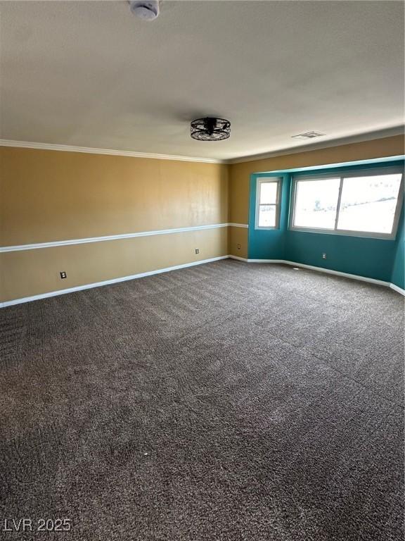 carpeted spare room with ornamental molding, visible vents, and baseboards