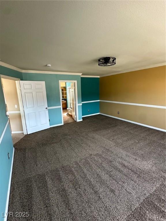 unfurnished bedroom with dark colored carpet, ornamental molding, and baseboards