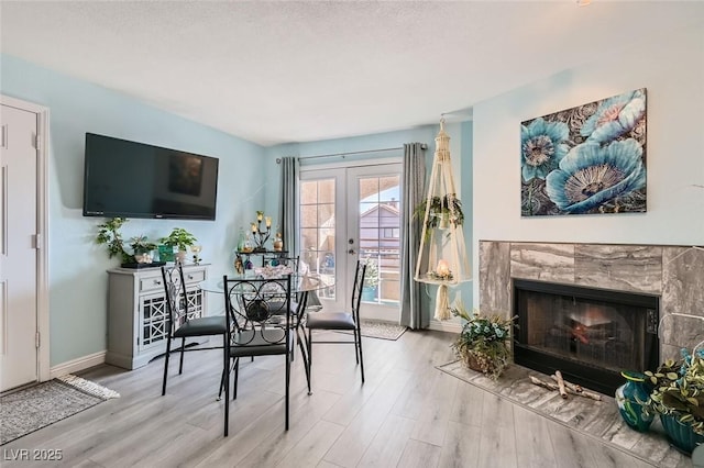 dining room with a fireplace, baseboards, wood finished floors, and french doors