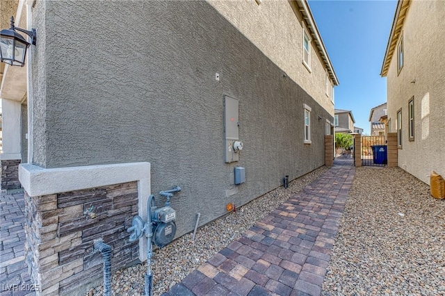 view of side of home featuring fence and stucco siding