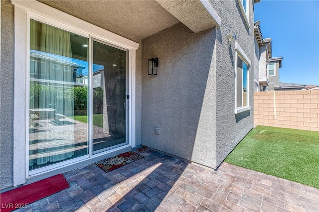 property entrance with a patio area, fence, and stucco siding