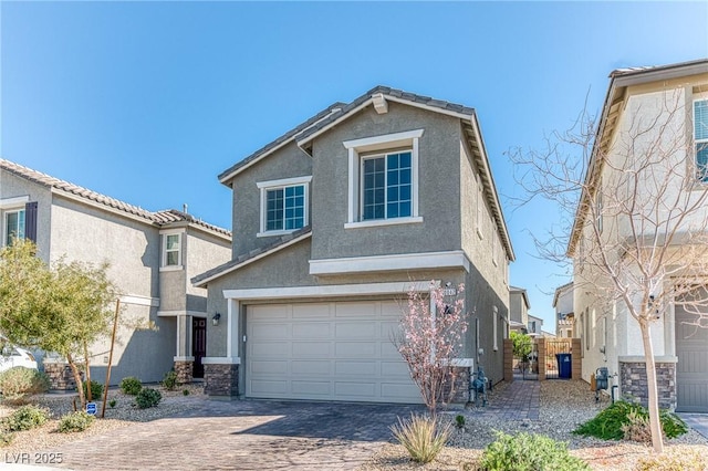 traditional-style house with stone siding, decorative driveway, an attached garage, and stucco siding