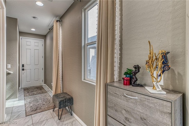 hallway featuring a textured wall, plenty of natural light, and baseboards