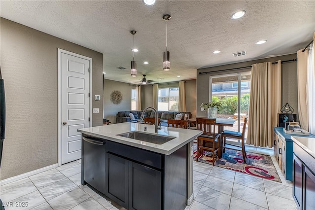 kitchen with light countertops, visible vents, stainless steel dishwasher, open floor plan, and a sink