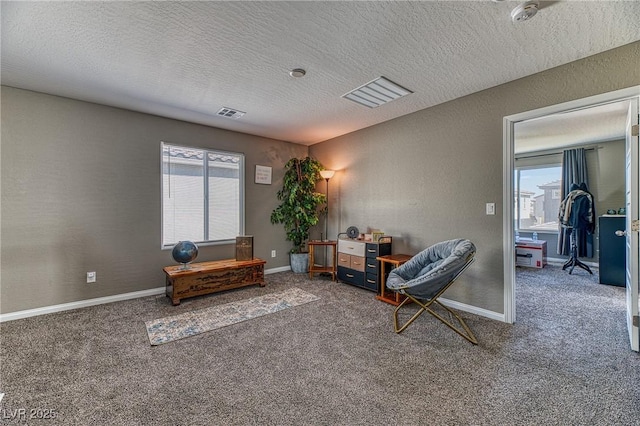 sitting room featuring plenty of natural light, a textured ceiling, visible vents, and carpet flooring