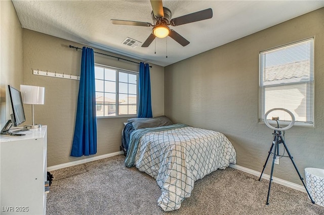 bedroom with carpet, visible vents, baseboards, and a textured wall