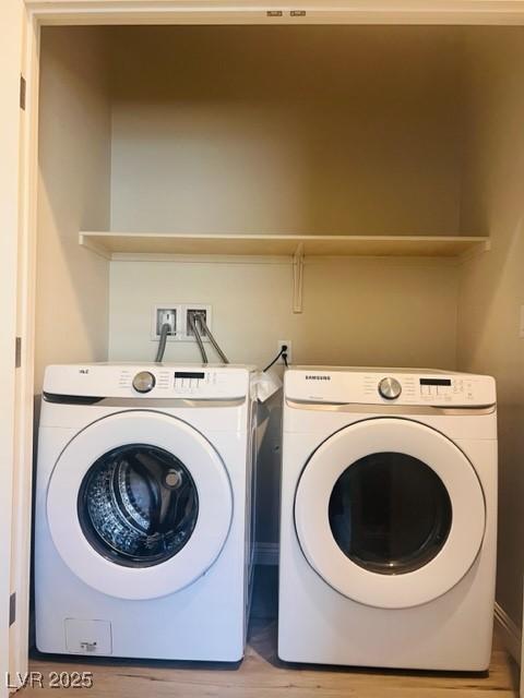 laundry area with laundry area, light wood finished floors, and washing machine and clothes dryer