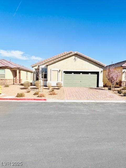 view of front of property featuring decorative driveway, an attached garage, and stucco siding