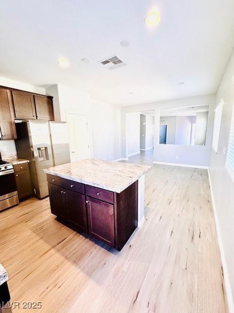 kitchen featuring light wood-style floors, white refrigerator with ice dispenser, visible vents, and stainless steel stove