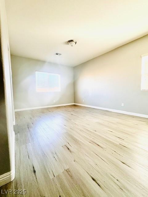 spare room with visible vents, baseboards, and wood finished floors