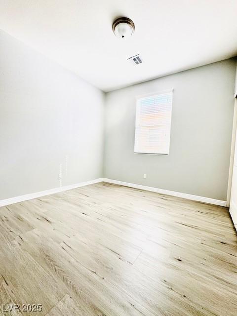 empty room featuring baseboards, visible vents, and wood finished floors